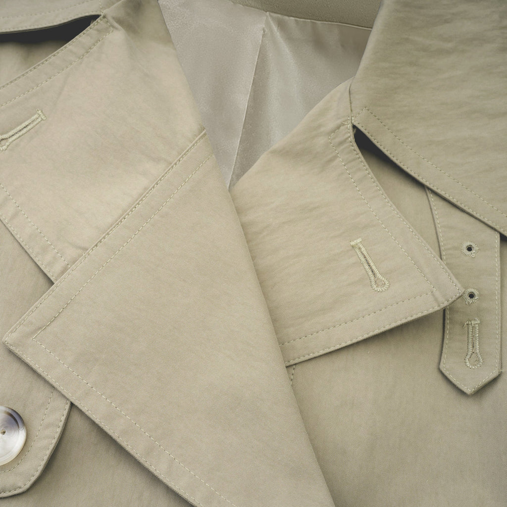 Abrigo trench con cinturón de la marca Bridal, color beige, con solapas y bolsillos frontales.