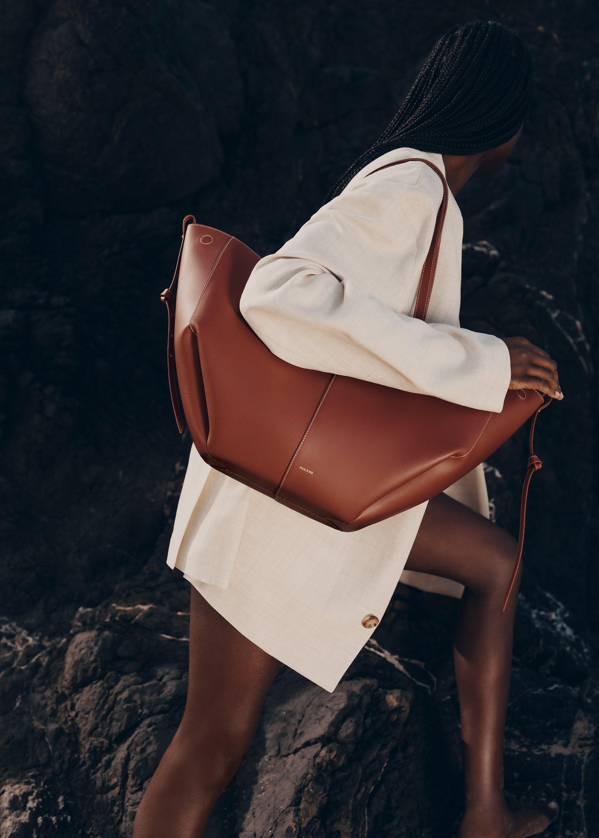 Bolso de mano Polène Cyme en piel granulada color coñac, con diseño elegante y detalles en la superficie.