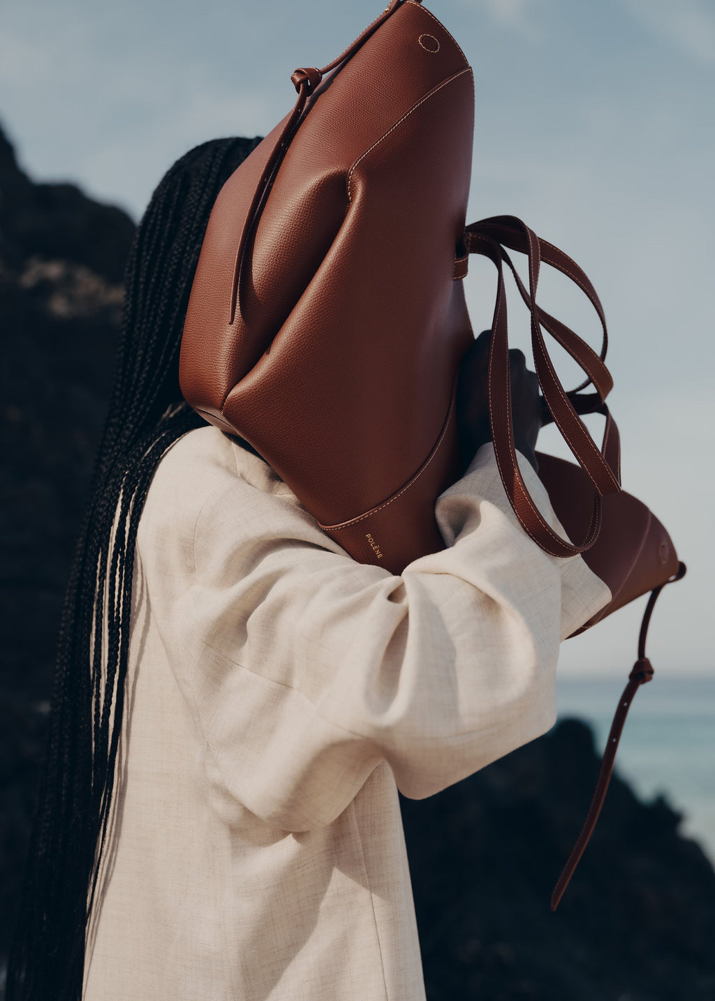Bolso de mano Polène Cyme en piel granulada color coñac, con diseño elegante y detalles en la superficie de la cartera.