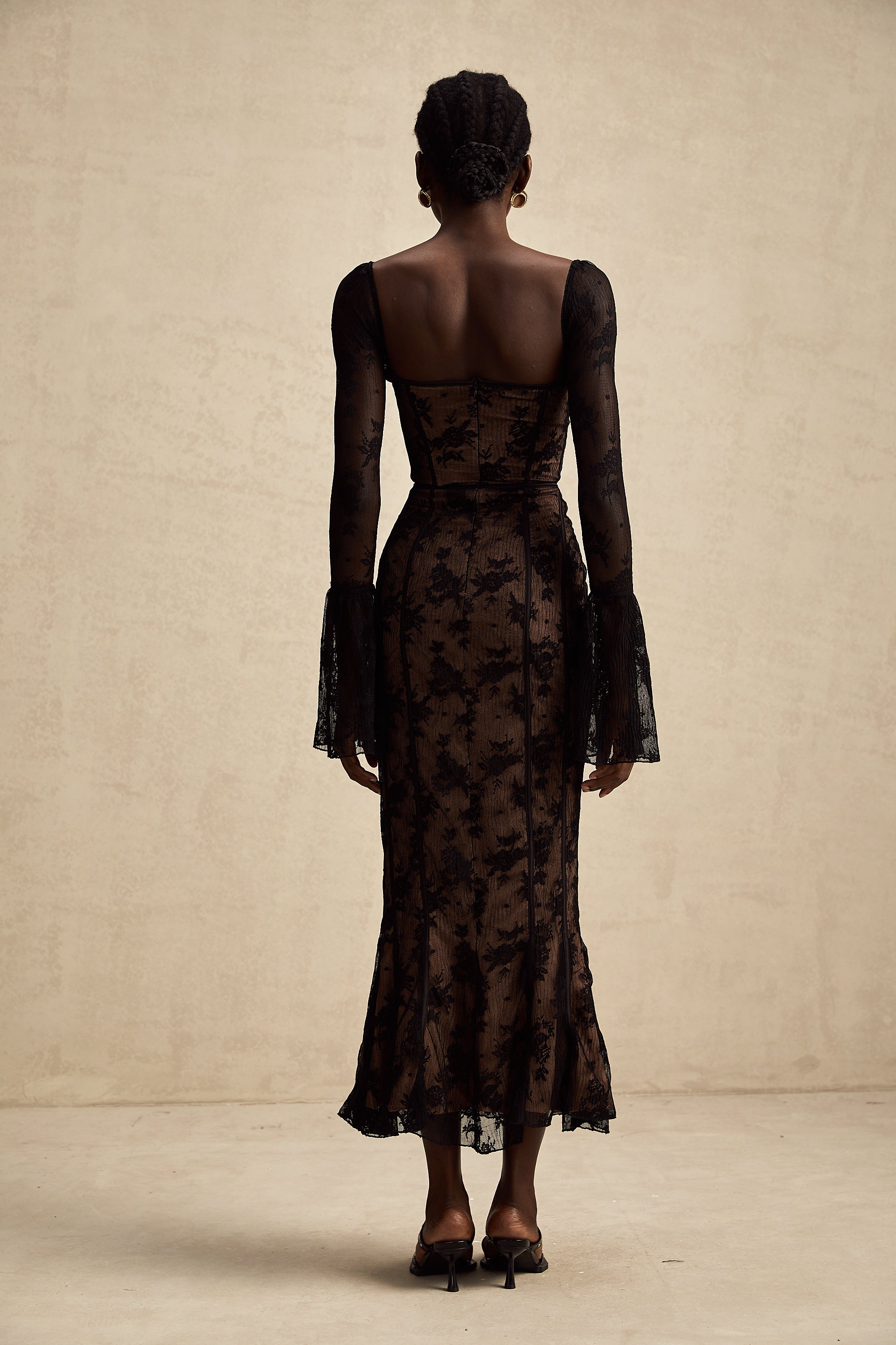 Vestido largo de encaje negro estilo maxi con forma acampanada de la marca Final Sale, en un fondo neutro.