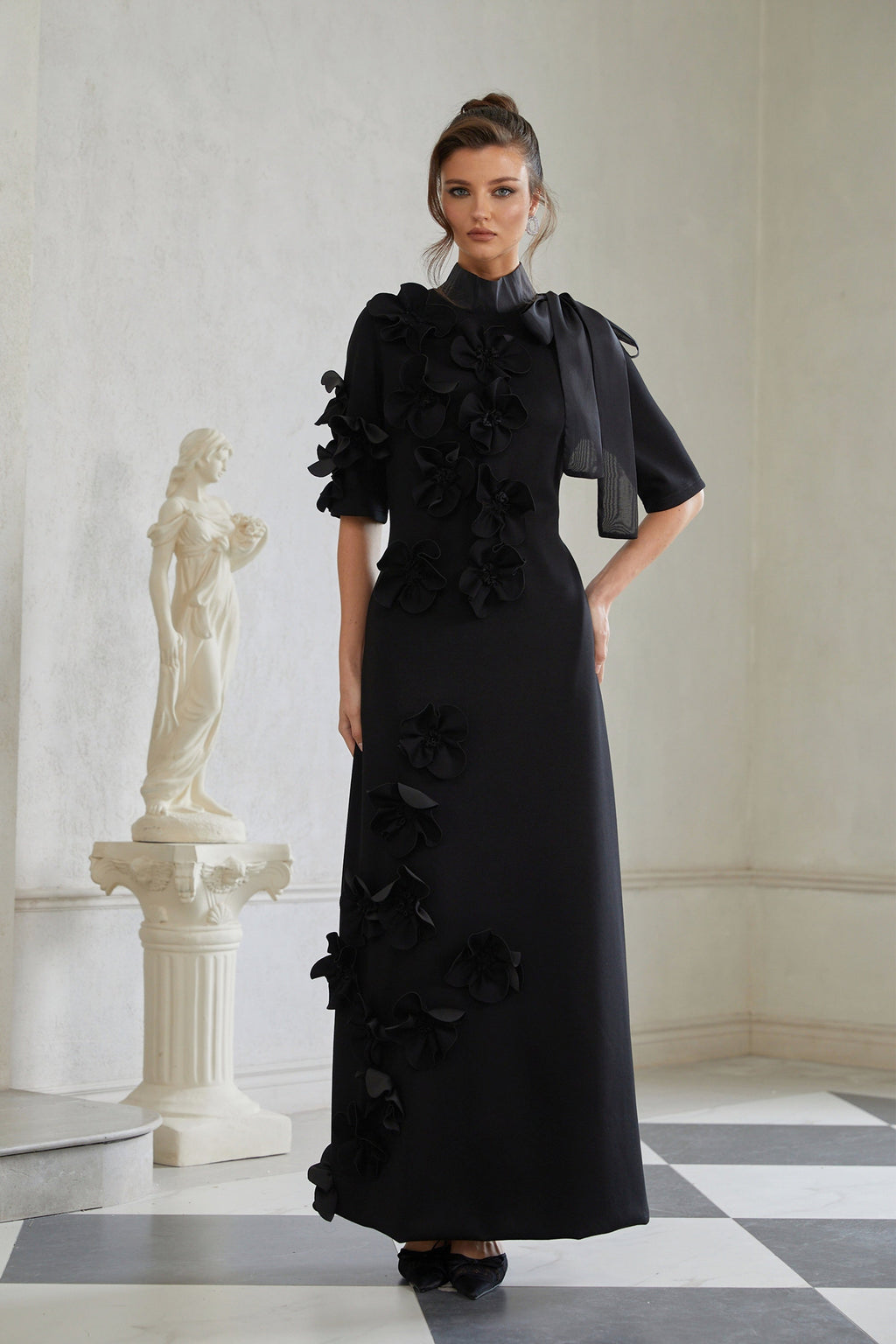 Vestido largo negro con lazo y aplicación floral de Bridal, estilo maxi, con detalles elegantes y románticos.