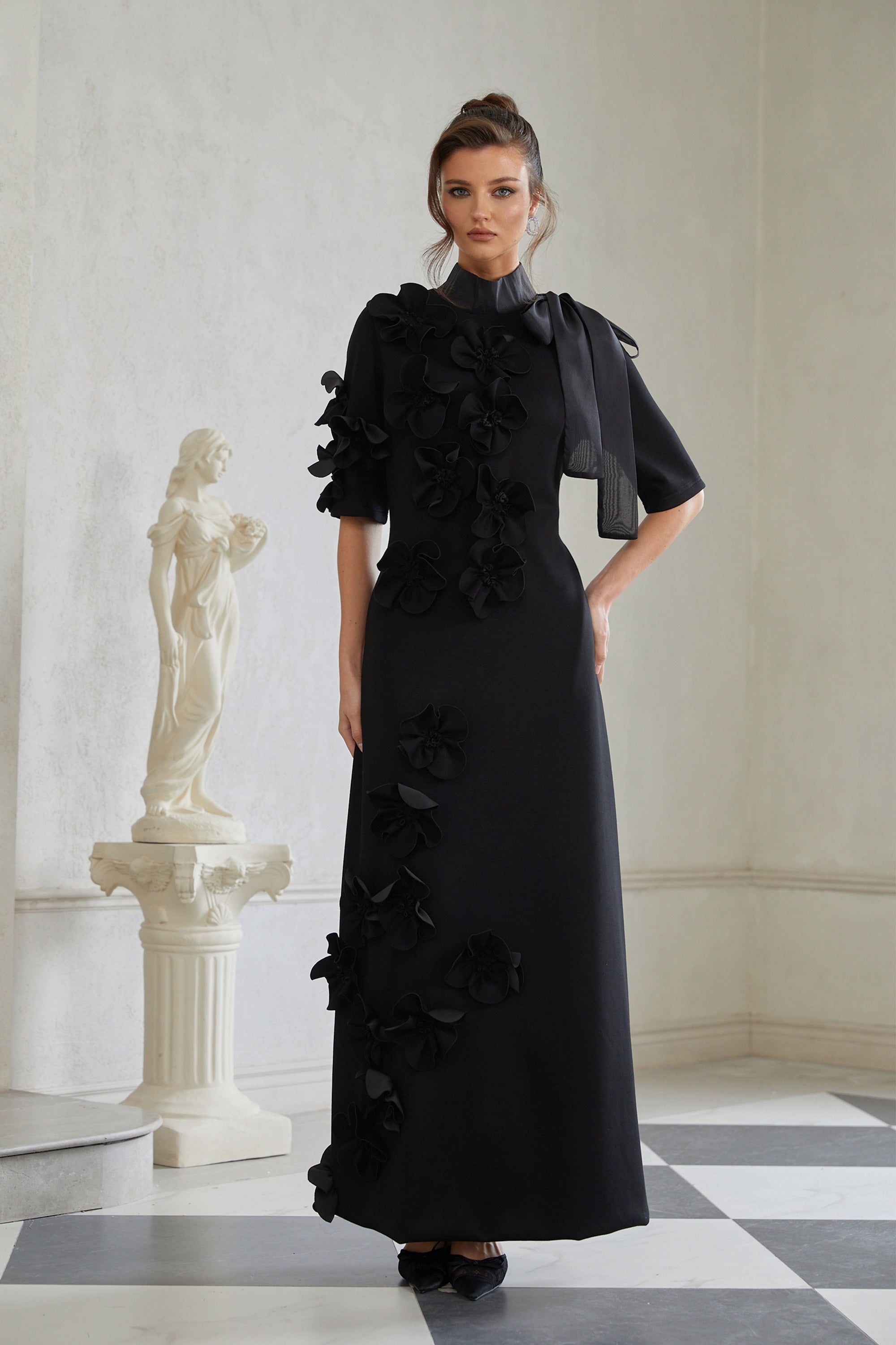 Vestido largo negro con lazo y aplicación floral de Bridal, estilo maxi, con detalles elegantes y románticos.