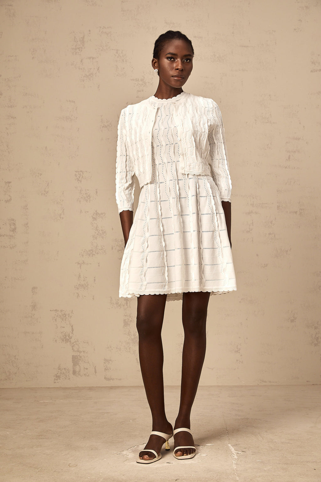 Cardigan de punto blanco Esmée con volantes y diseño ajustado, ideal para un estilo elegante y cómodo.