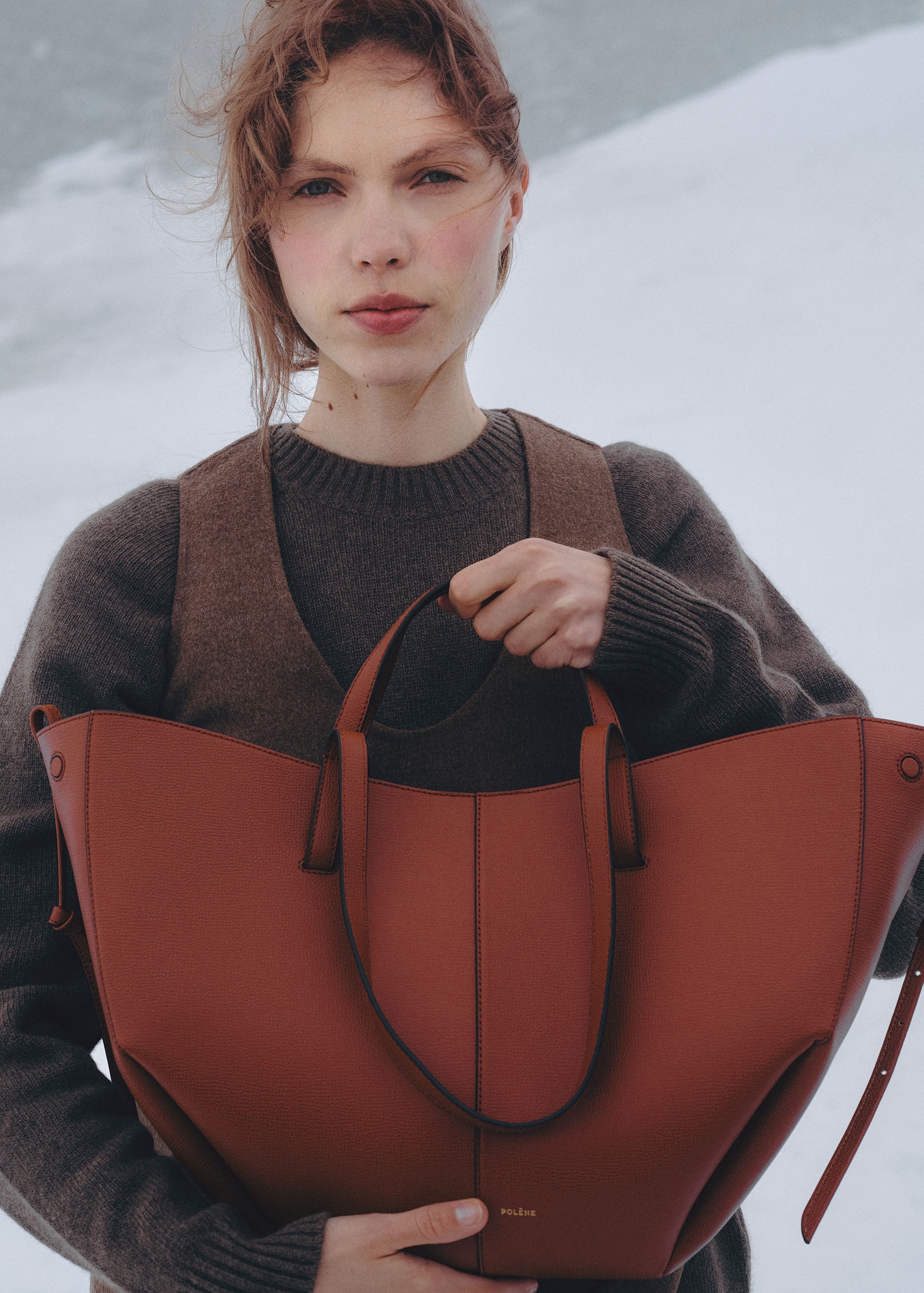 Bolso de mano Polène Cyme en arcilla roja con textura granulada, diseño elegante y material de alta calidad.