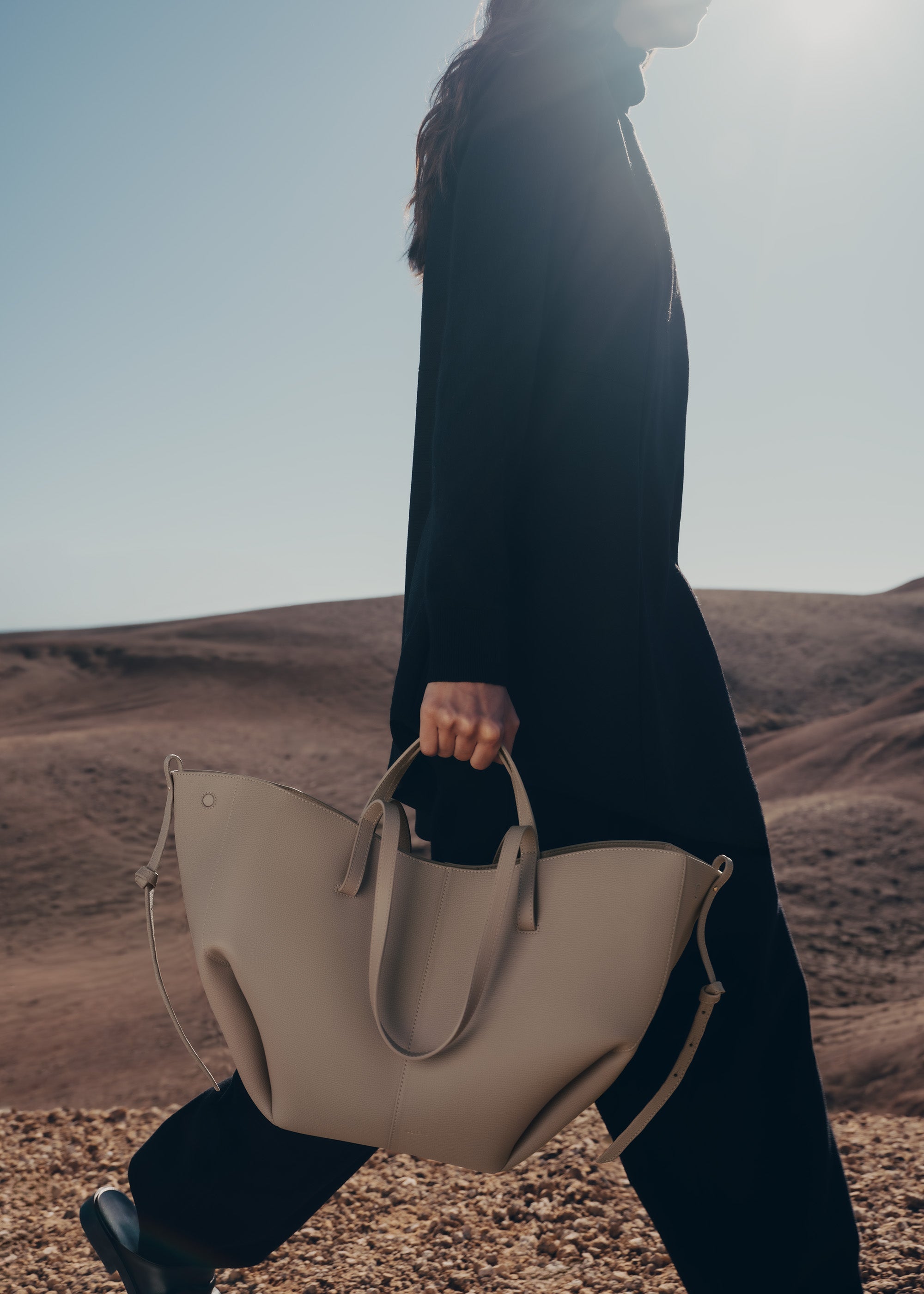 Bolso de mano Polène Cyme en piel granulada gris topo, con detalles elegantes y diseño moderno.