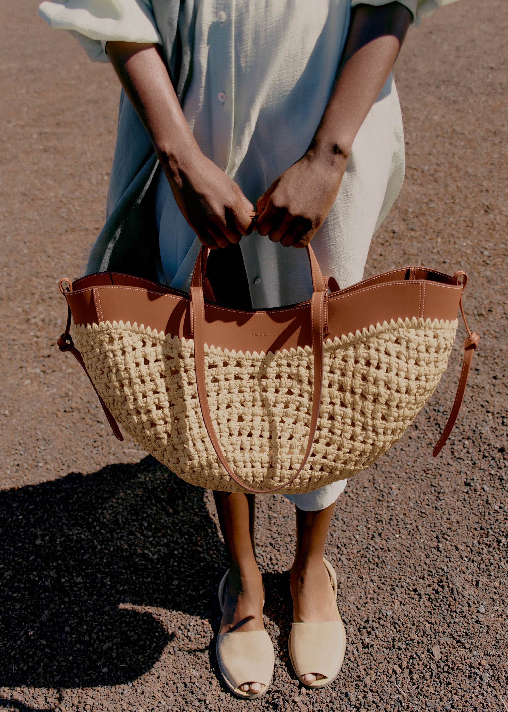Bolso de mano Polène Cyme en rafia, con diseño elegante y detalles en tonos neutros, perfecto para llevar en ocasiones especiales.