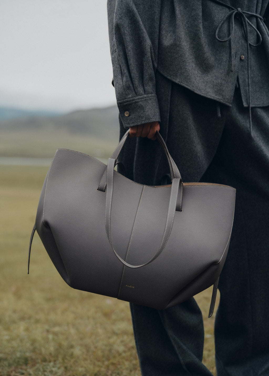 Bolso de mano Polène Cyme con acabado en piedra piel granulada y diseño elegante, vista frontal del bolso.