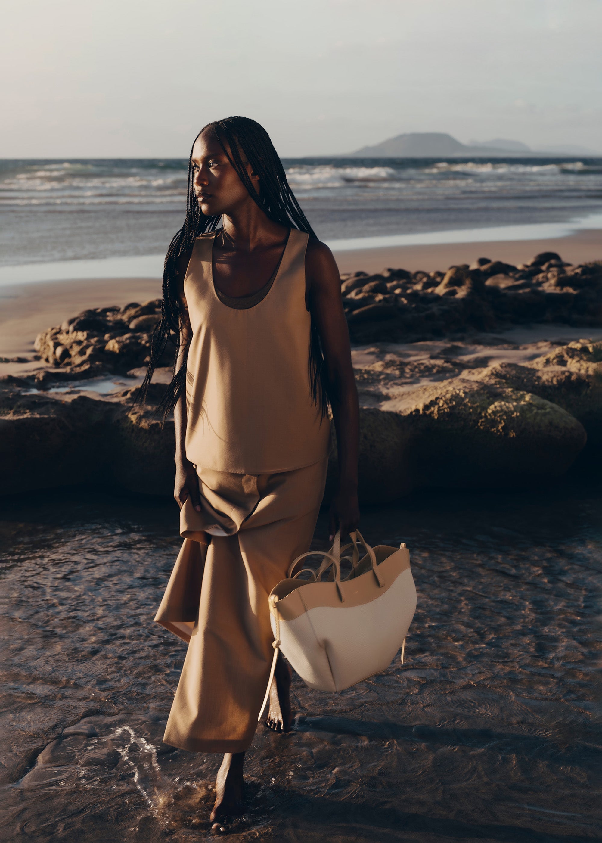 Bolso de mano trenzado en beis de la marca Polène, estilo elegante y sofisticado, con detalles de tejido en el diseño.