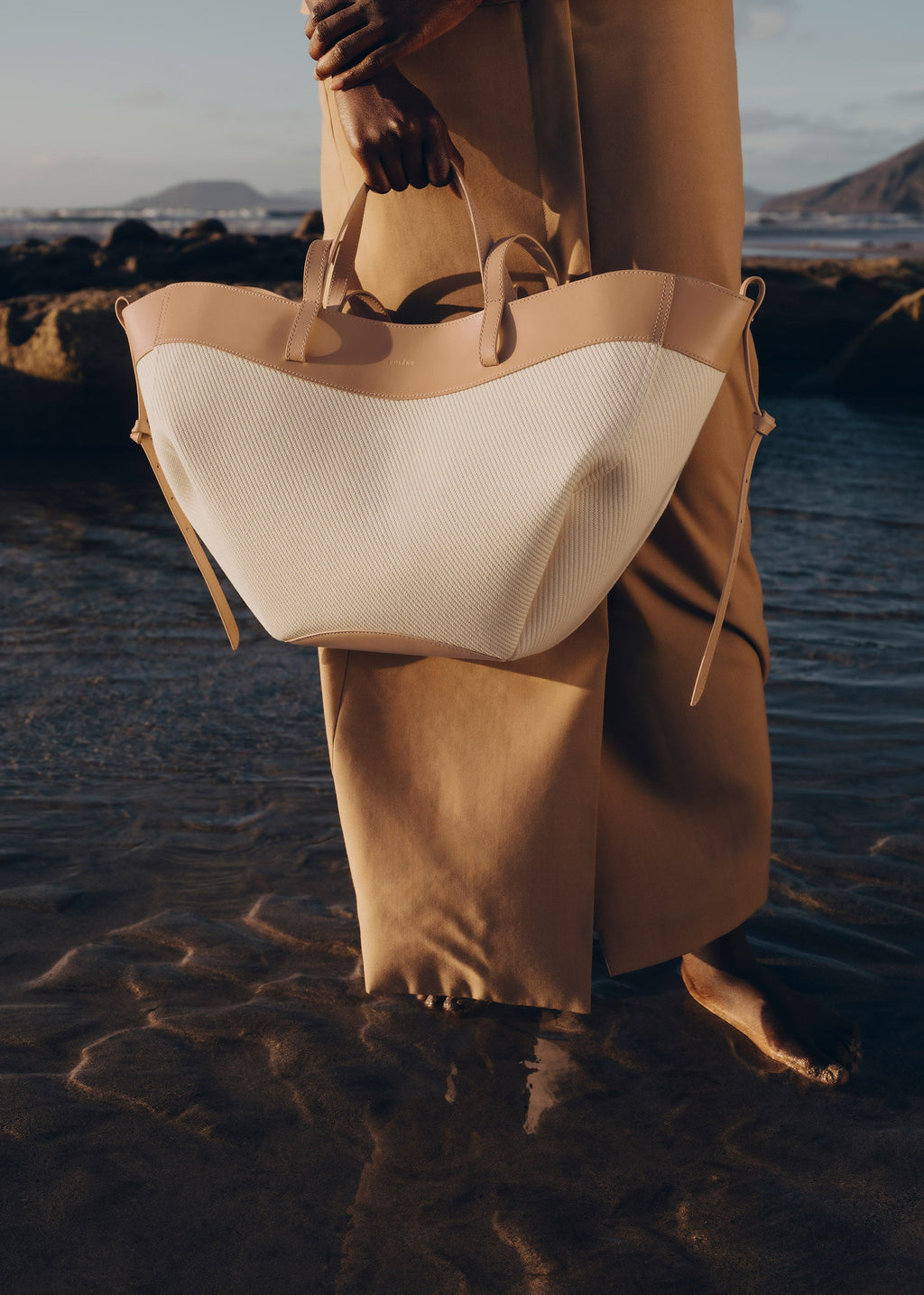 Bolso de mano trenzado beis de la marca Polène, estilo elegante y moderno, con detalles de textura en la superficie.