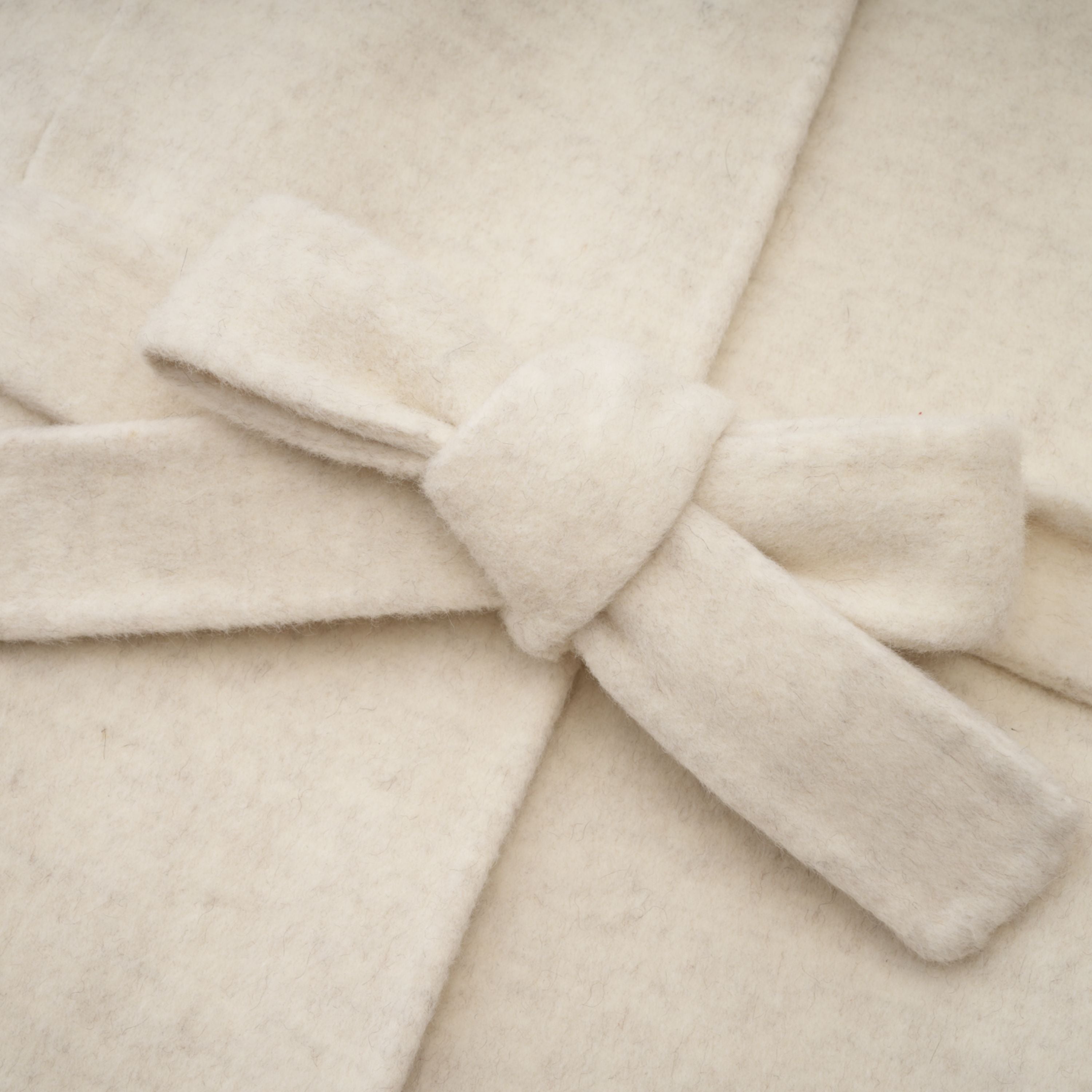 Abrigo blanco con cinturón y detalles de piel de la marca Bridal, con cierre elegante y diseño clásico.