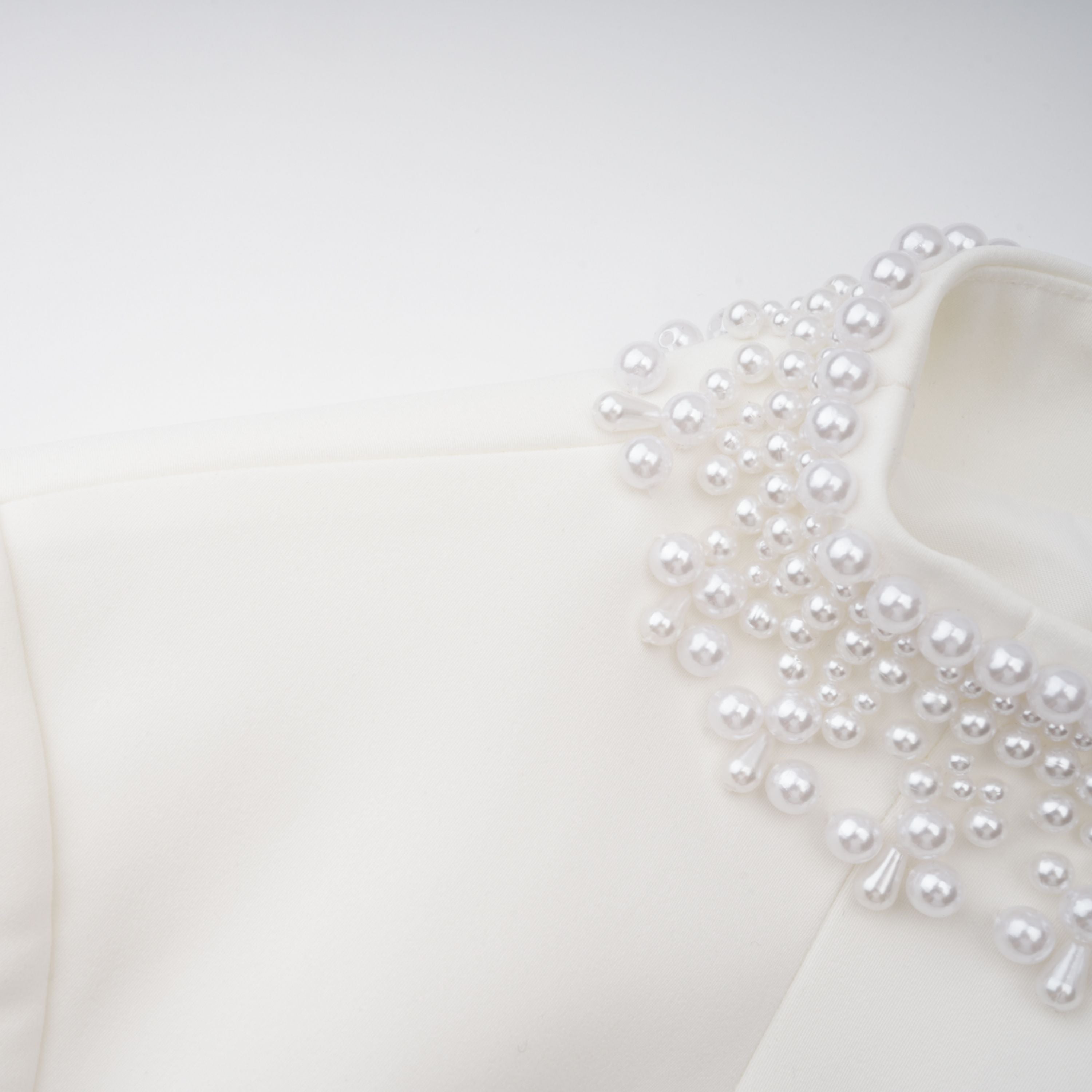 Vestido mini blanco con perlas falsas, estilo elegante de la marca Final Sale, con detalles en el escote y falda ajustada.