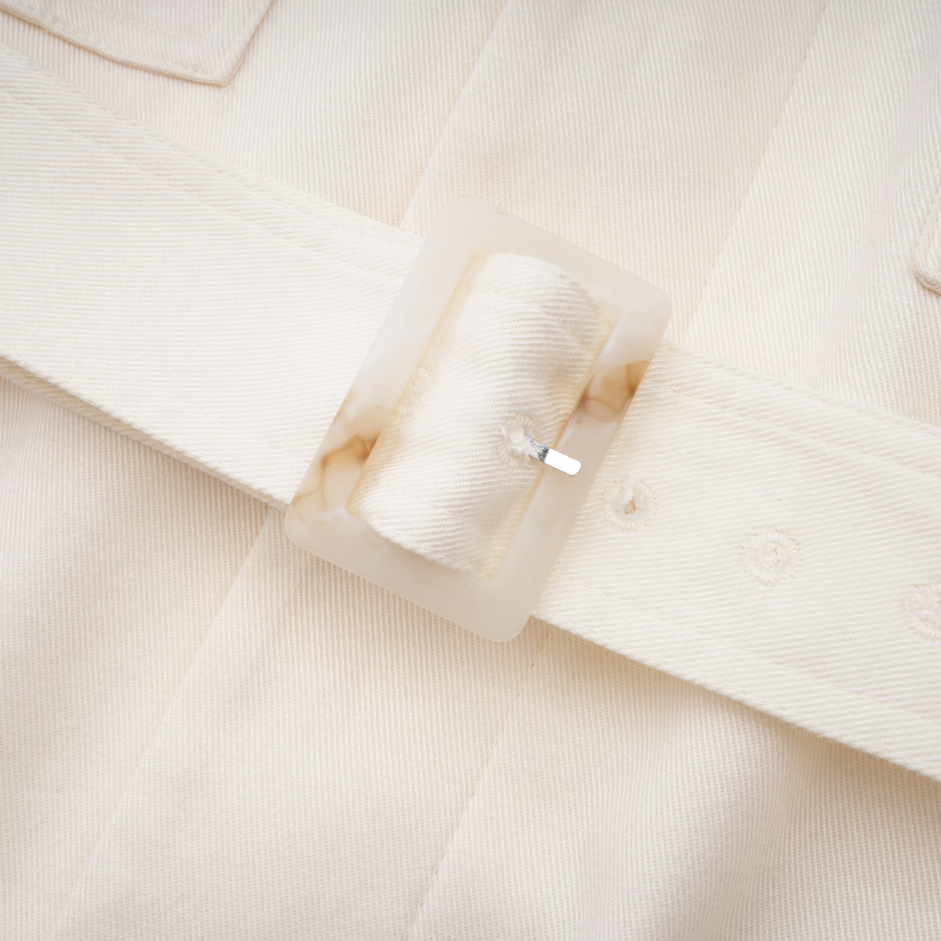 Abrigo trench blanco con cinturón de la marca Final Sale, cuello clásico y botones, vista frontal en color blanco.