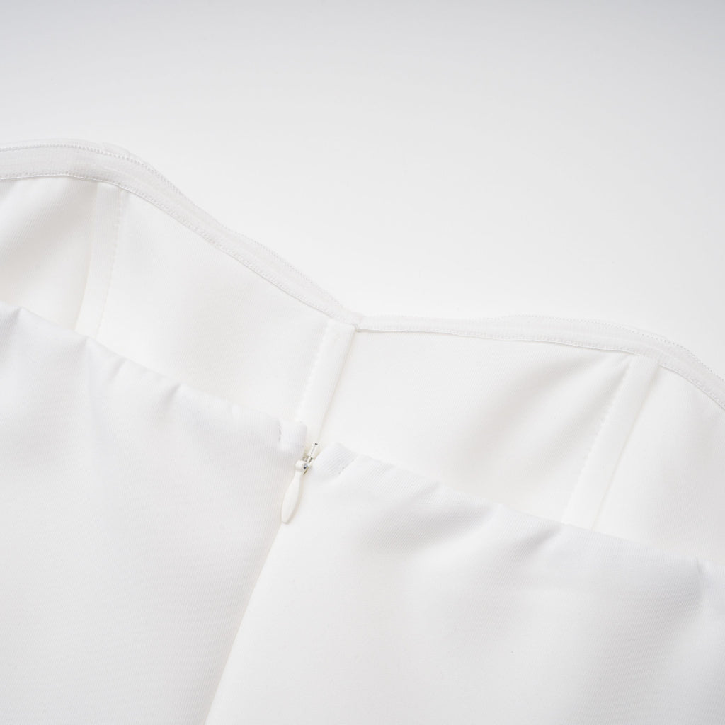 Vestido de novia en conjunto con capa estructurada blanca y corsé, con detalles elegantes y sofisticados.