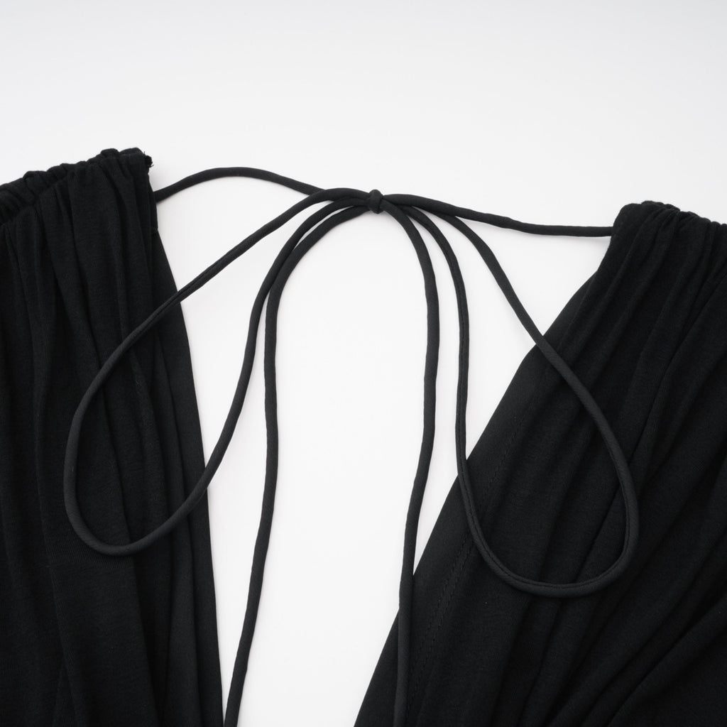 Mono negro Gianina de Bridal con escote en V profundo y diseño drapeado, manga larga y estilo elegante en la imagen.