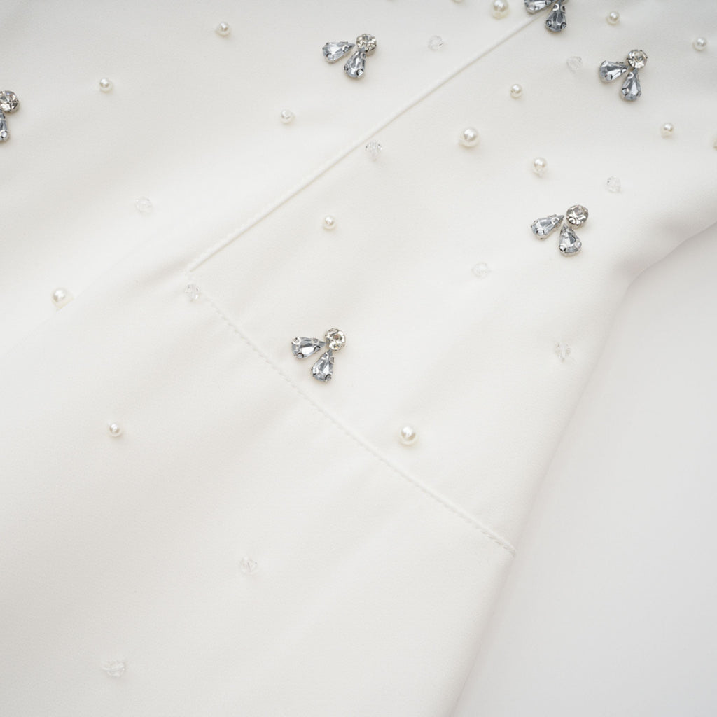 Conjunto de vestido y falda blancos con adornos de la marca Bridal, con detalles elegantes y diseño formal para ocasiones especiales.