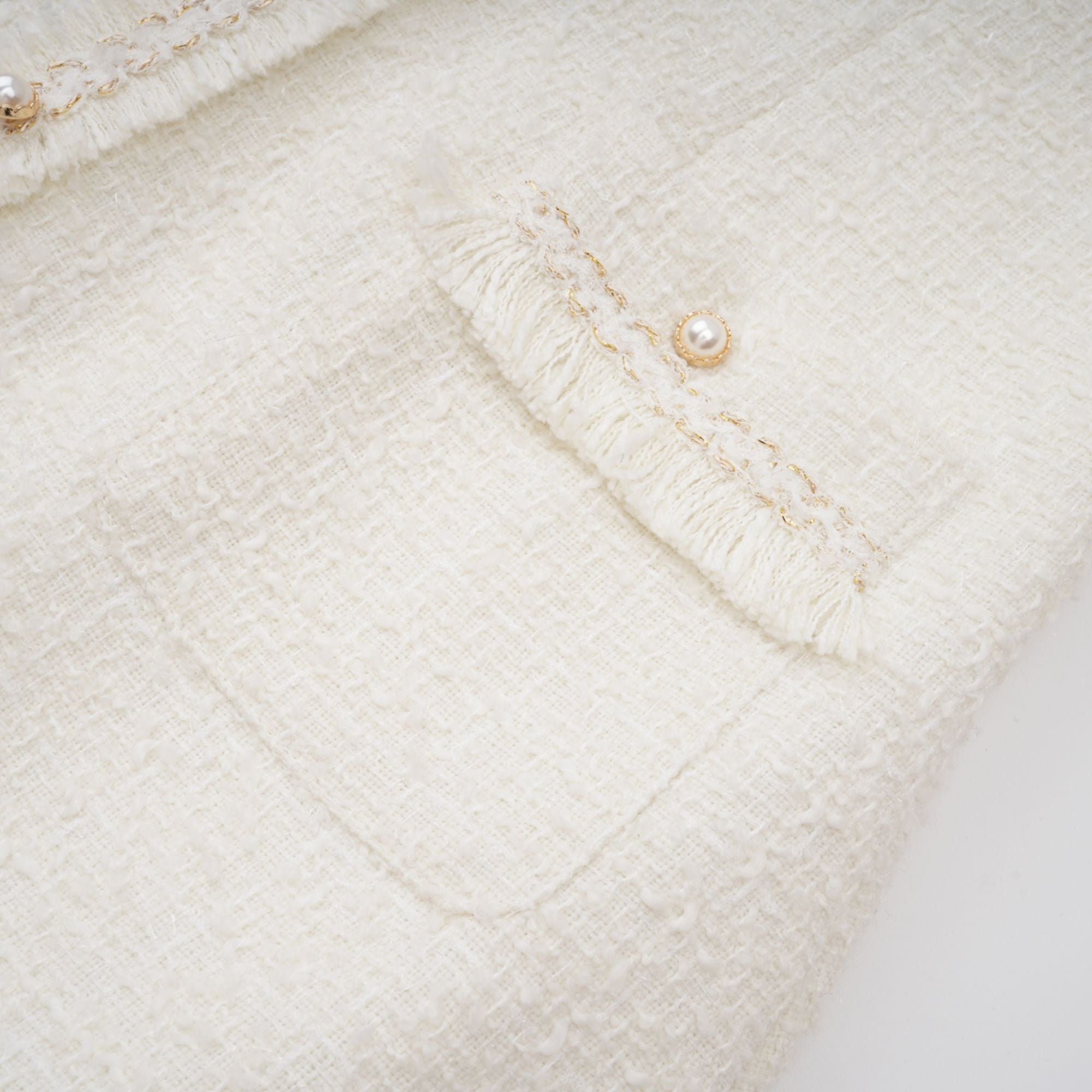 Vestido mini de tweed blanco con perlas falsas, diseñado por Final Sale, muestra detalles de textura y estilo elegante.