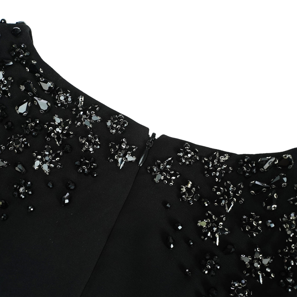 Vestido maxi negro Yseult con embellishments, elegante y largo, mostrado en una modelo con fondo neutro.