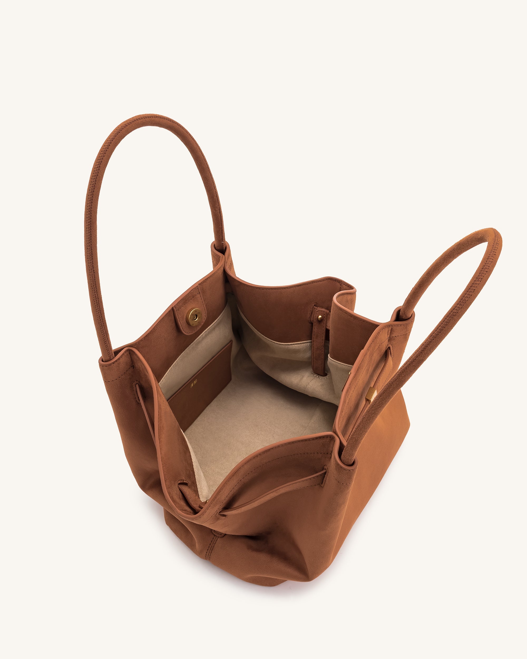 Mochila tote mediana en ante sintético marrón de JW PEI, vista interior con compartimentos y detalles de diseño elegante.
