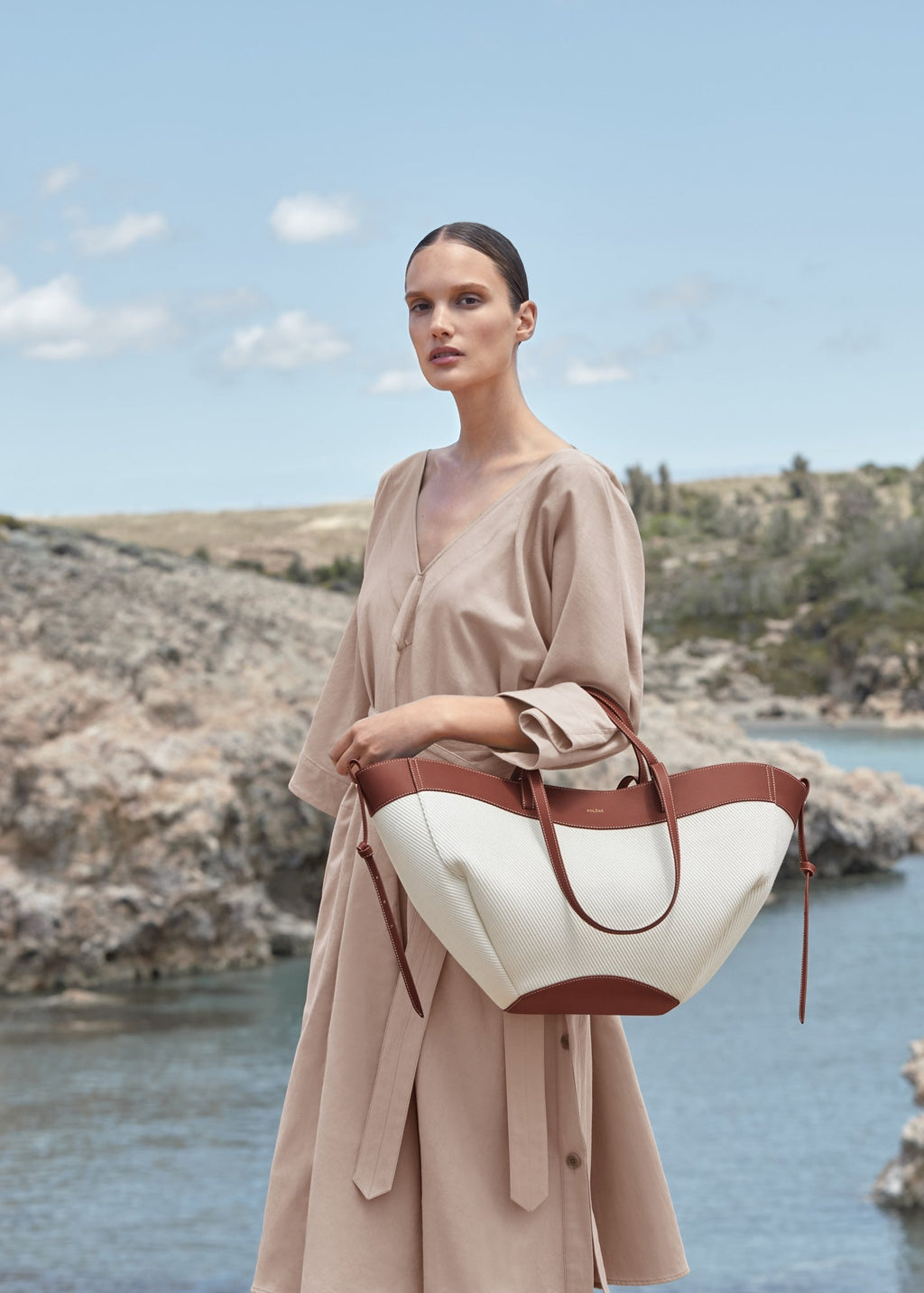 Bolso de mano Cyme trenzado en color coñac de la marca Polène, con diseño elegante y detalles en cuero.