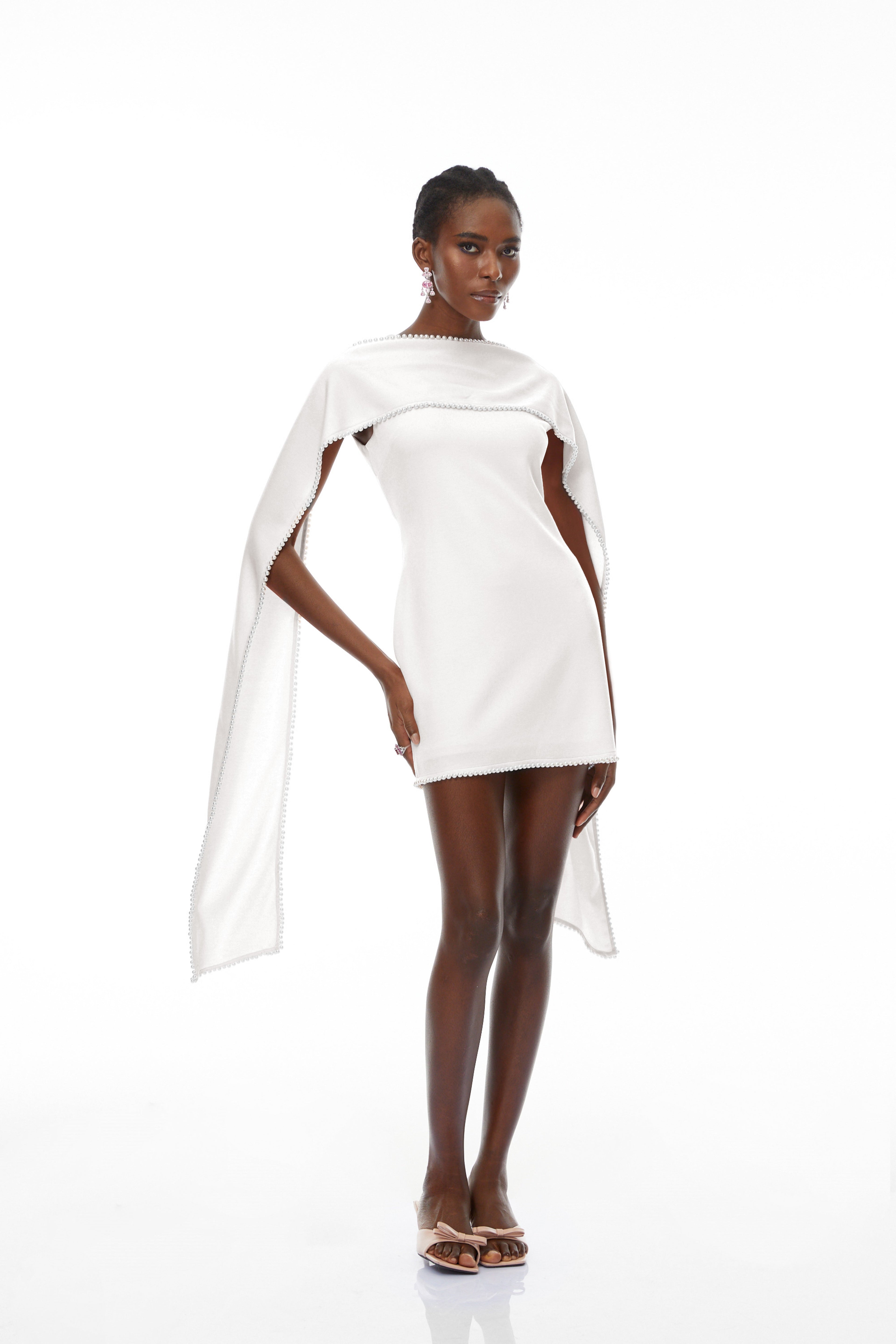 Vestido mini sin mangas blanco Piroska de la marca Bridal con detalles de perlas en el dobladillo y diseño elegante.