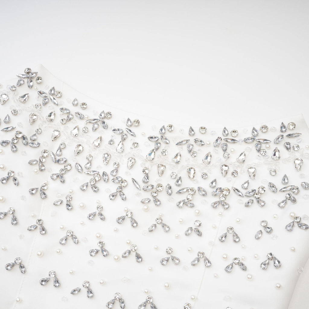 Vestido mini blanco Melisande con decoraciones elegantes y detalles brillantes, de estilo sofisticado y moderno.