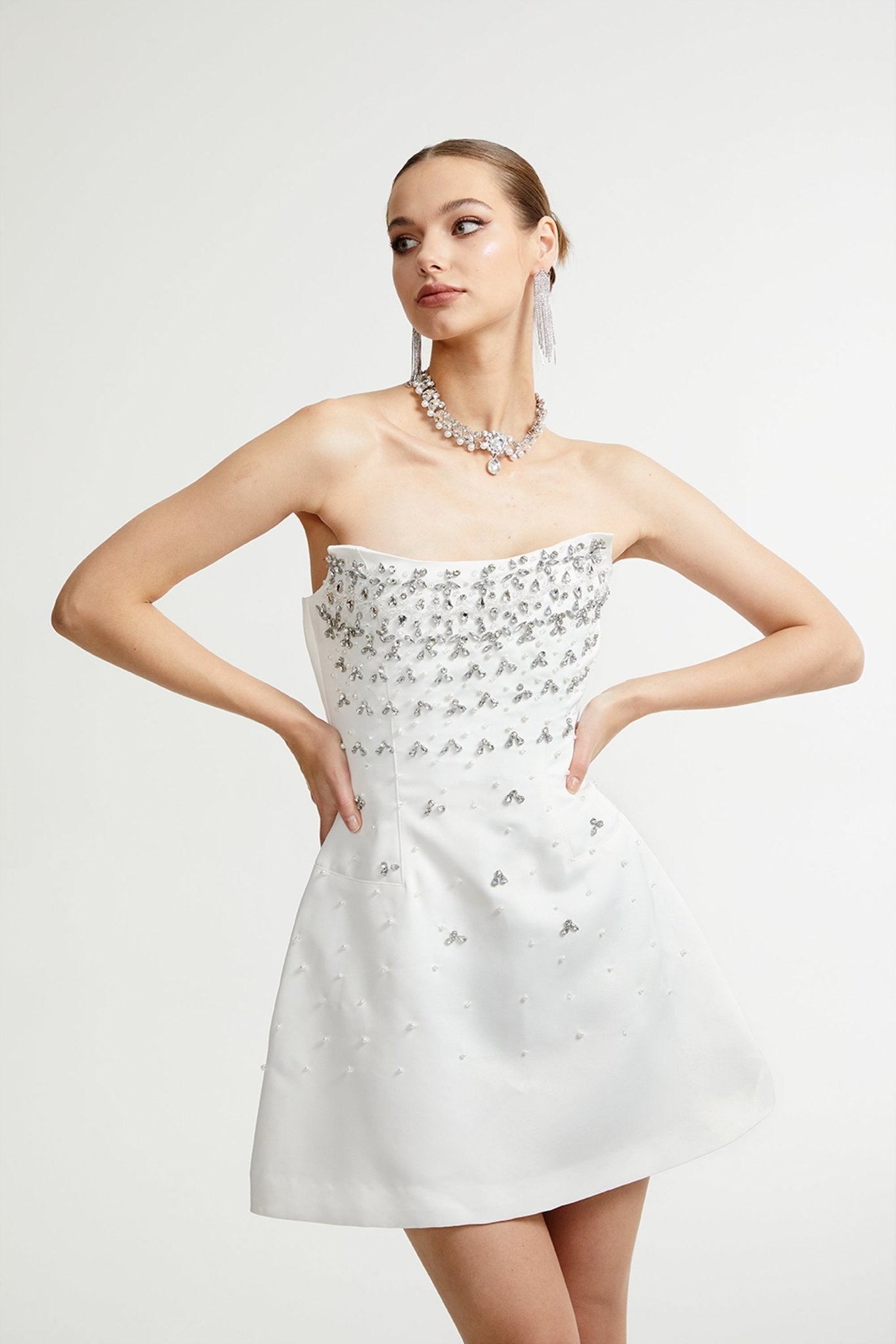 Vestido mini blanco Melisande con adornos, ajustado y elegante para ocasiones especiales, vista en la imagen con detalles decorativos.